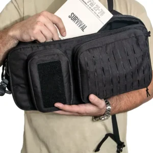 Person holding a black tactical bag (inserting a survival manual)
