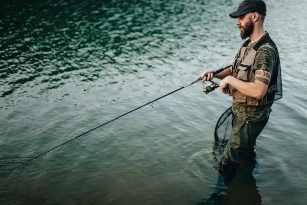 Sportfischen am Fluss, Mann fischt an einem sonnigen Sommertag