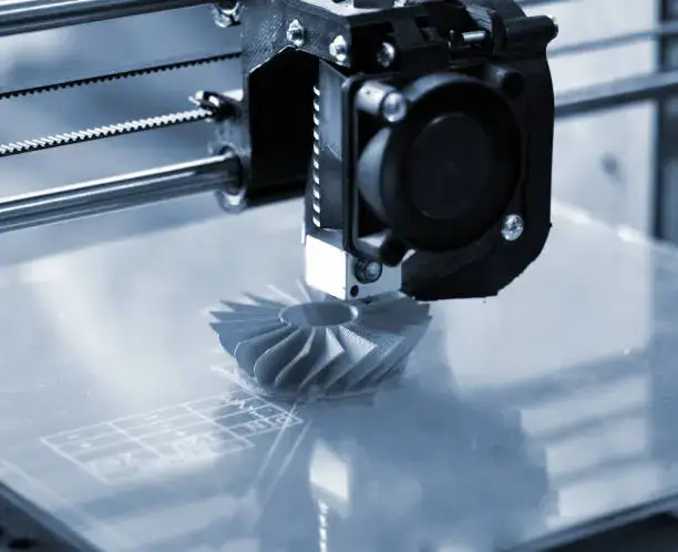 Stampa 3D La stampante 3D stampa forme blu su sfondo blu