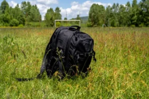 Black backpack left on the grass meadow.