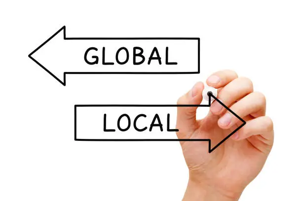 Hand drawing Local or Global arrows concept with marker on transparent wipe board. Think global, act local.