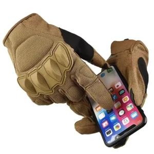 Hands wearing tan tactical gloves with hard knuckles, using a smartphone, highlighting touchscreen compatibility.