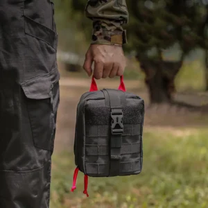 Henkilö, jolla on musta taktinen ensiapupussi hallussaan